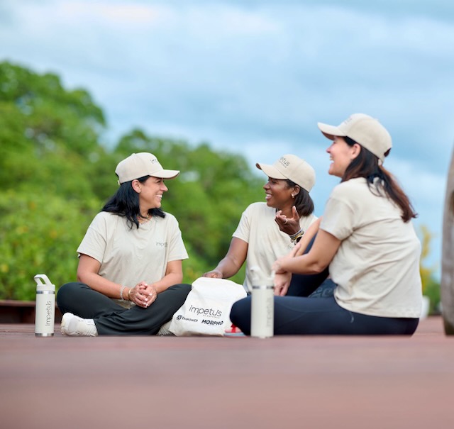 Three women sitting on a wooden bridge at an Impetus retreat